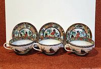 front view of three teacups each on its saucer showing interior rooster scenes