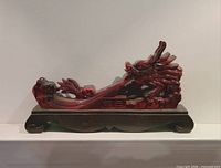 Front view of red dragon sculpture on wooden stand