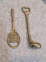 Tennis racquet and golf club brass bottle openers side by side