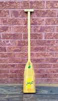 Full view of wooden canoe paddle against brick wall