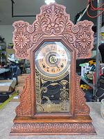 Full front view of carved oak mantel clock showing entire case and glass door