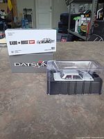 Model car in clear display case in front of branded outer box
