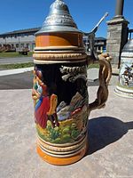Full view of stein showing lid, handle and relief scene