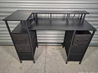 Full view of black desk showing monitor shelf, side shelf, six drawers and metal frame