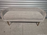Front view of light gray fabric bench with brass-tone legs