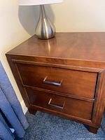 Front angled view of wooden bedside table showing top surface and drawers
