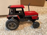 Left front view of red and black Case International 1:64 toy tractor showing cab and front axle
