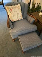 armchair with pillow and footstool visible