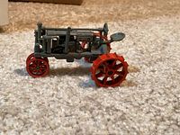 Left side view of grey Farmall diecast tractor with red wheels