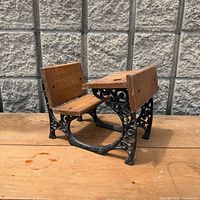 Front angled view of the miniature school desk showing cast iron frame and wood components