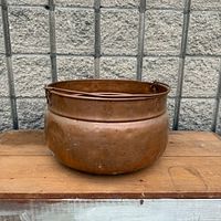 Side view of copper pot showing overall shape, patina and handle lugs