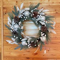 Front view of green, white and silver artificial pine wreath on wood wall