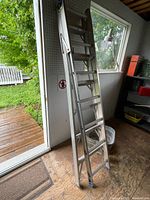 Side view of folded aluminum ladder leaning against wall showing entire length