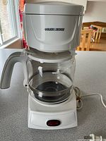 Front view of coffee maker showing body, carafe, power switch, cord