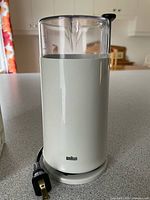 Front view of white Braun coffee grinder with cord