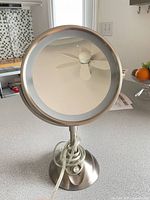 Front view of brushed nickel vanity mirror with LED ring and cord