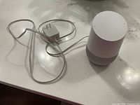 Google Home speaker with attached power adapter on countertop