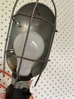 Close-up of bulb, metal reflector and wire cage showing rust