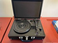 Open briefcase turntable showing platter, tonearm, controls