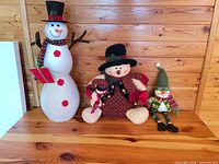 All three holiday plush decorations displayed together on wooden surface