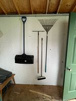 All four garden tools hanging on pegboard wall