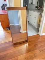 Front view of rectangular wood and chrome framed freestanding mirror