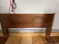 Front view of wood veneer queen headboard showing full rectangular panel and legs with mounting slots