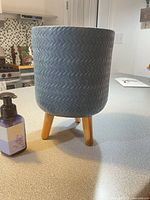 Front view of slate blue ceramic planter on wood legs