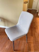 Front side view of light grey upholstered chair showing fabric and metal legs