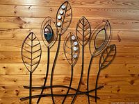 Full view showing entire metal leaf wall decor piece against wood wall