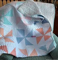 full view of pastel pinwheel quilt draped over chair