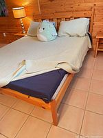 Full view of assembled queen pine bed frame with slatted headboard and box spring beneath bedding