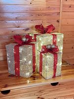 Three gold mesh gift boxes with red ribbon lit up