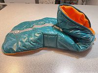 Side view of teal puffer dog coat showing overall design, reflective strip and collar