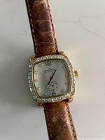 Front view showing cushion crystal-set case, dial design, leather strap