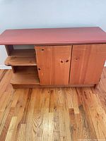 Front view of solid wood cabinet showing red top, two doors, open shelves