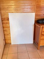 Front view of large white primed canvas leaning against wall