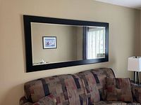 Full view of rectangular mirror with black frame hanging on wall