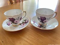 Front view of two matching teacups on saucers showing floral design and gold gilt