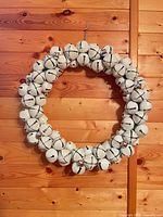 Front view of white and silver jingle bell wreath on wood wall