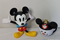 Mickey Mouse figure cup next to snowman cup
