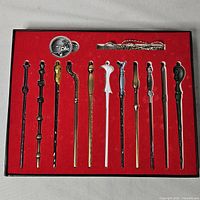 Full view of boxed set showing 11 mini wands, pendant and chain in red felt display