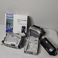 Group shot showing Olympus TG-3 box, Panasonic camcorder, Canon ZR70MC, JVC GR-DVM70
