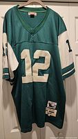 Front view of green Mitchell & Ness Joe Namath #12 Jets jersey hanging