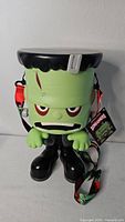 Front view showing Frankenstein bucket face, strap, and tag