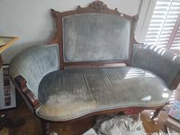 Full view of settee showing worn blue upholstery and wood frame