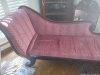 Full view of chaise lounge left side showing upholstery and carved frame
