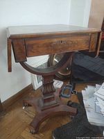 Full view of mahogany nightstand showing drop leaf, drawer with keyhole, pedestal and base
