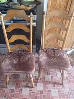Front view of both ladder-back chairs showing wood finish and damask seats