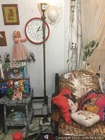 Full view of marble and brass floor lamp standing beside a chair with character pillows and other decorative items around it.